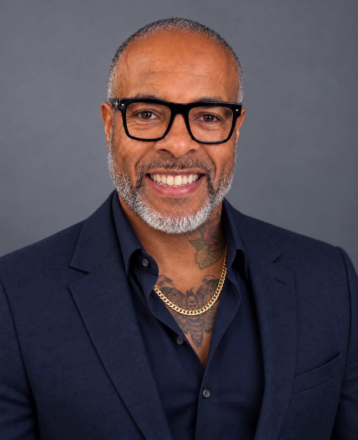 Portrait of Jerry Newman in a navy jacket and shirt, glasses, and a gold chain