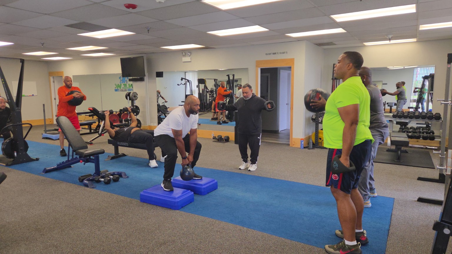 Men exercising together with kettlebells, dumbbells, and medicine balls in the studio